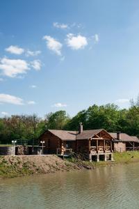 a log cabin next to a lake with a house at Ray Eco Resort in Mukacheve