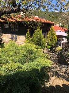 una casa con un patio con árboles y arbustos en Попската къща-възрожденски дух и съвременни удобства en Medven
