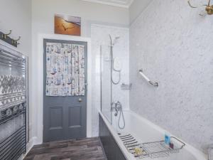 een badkamer met een bad, een douche en een deur bij Pier Haven in Blairmore