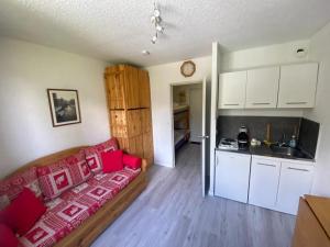Una sala de estar con un sofá rojo y una cocina. en Studio, en Barcelonnette