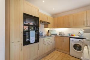 a kitchen with wooden cabinets and a washer and dryer at The Kelling in Blakeney