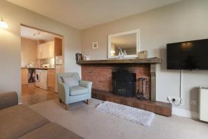 a living room with a fireplace and a television at Burnham A in Blakeney