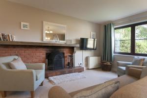 a living room with a fireplace and a tv at Burnham A in Blakeney