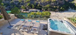 a balcony with a hot tub and chairs and a beach at *Casa Aguamarina* Villa am Meer in Cala Pi