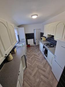 a kitchen with white cabinets and a wooden floor at Luna Apartments Newcastle Gateshead 1 in Gateshead