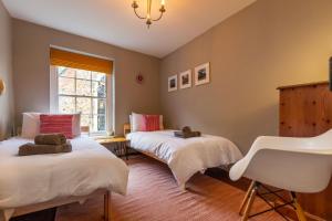 1 dormitorio con 2 camas y 1 silla en Princes Cottage en Norwich