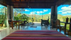 a bedroom with a large window and a table and chairs at Ecopousada Toca do Guará in Alto Paraíso de Goiás