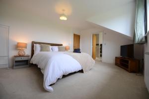 a white bedroom with a large bed and a flat screen tv at Rollestone New Forest (HOT TUB) in Salisbury