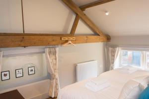 a bedroom with a white bed and a window at Boathouse Barn in Coltishall