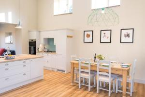 a kitchen with a wooden table and white cabinets at Boathouse Barn in Coltishall