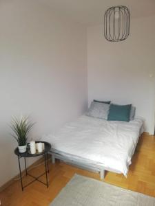 a bed in a white room with a table at Apartament Józio in Gdańsk