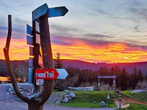 a street sign on a pole with a sunset in the background at Ferienhaus Am Kirchberg in Kurort Steinbach-Hallenberg