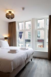 een slaapkamer met een groot wit bed en ramen bij Finest Apartments in Haarlem