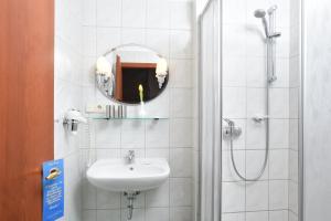a bathroom with a sink and a shower with a mirror at Hotel Villa Weiße in Kamenz