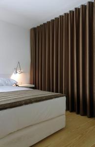 um quarto com uma cama e cortinas castanhas em Convento de Tibaes em Braga
