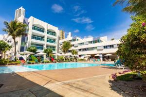 a hotel with a swimming pool in front of a building at Hotel Ponta Negra Beach by Oxequealuguel in Natal