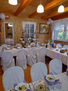 ein Esszimmer mit weißen Tischen und weißen Stühlen in der Unterkunft Gospodarstwo Agroturystyczne Ćmilówka 