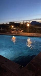 una piscina notturna con sedie e luci di Villa Pavone a Coreglia Antelminelli