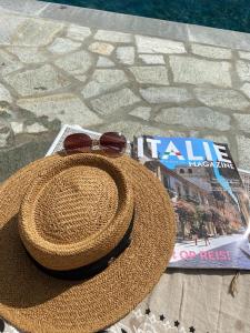 un cappello di paglia e occhiali da sole seduti accanto a una rivista di Villa Pavone a Coreglia Antelminelli
