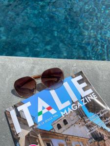 a pair of sunglasses and a magazine next to a swimming pool at Villa Pavone in Coreglia Antelminelli