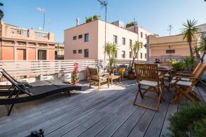 Prive terrace in El Born, near the beach في برشلونة: سطح خشبي مع كراسي وطاولات على مبنى