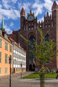 un gran edificio con una torre de reloj encima en Korona Starego Gdańska en Gdansk