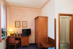 a room with a desk with a television and a cabinet at Hotel Villa Weiße in Kamenz