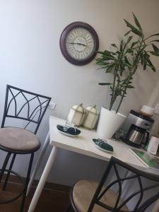 a desk with a clock on the wall and a plant at West Edmon. Mall = Room in Edmonton