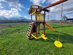 a playground in a field with a swing at Holiday House Sabala 2 in Stará Lesná