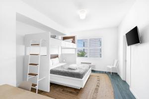 a white bedroom with a bunk bed and a tv at The Variety by LuxUrban in Miami Beach