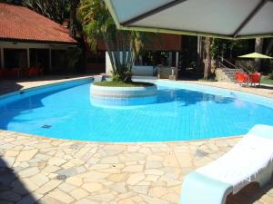 a large swimming pool with two chairs and an umbrella at Suíça Hotel by Nordic in Foz do Iguaçu