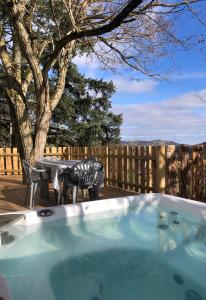 a hot tub on a patio with a table and chairs at La foret des hérissons in Longessaigne