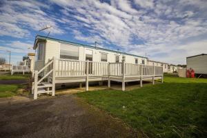 a mobile home with a porch and a fence at Caravan With Decking At Manor Park, Nearby Hunstanton Beach Ref 23013c in Hunstanton