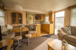 a living room with a couch and a table at Caravan With Decking At Manor Park, Nearby Hunstanton Beach Ref 23013c in Hunstanton