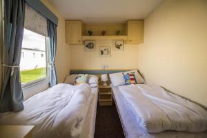 two beds in a room with a window at Caravan With Decking At Manor Park, Nearby Hunstanton Beach Ref 23013c in Hunstanton
