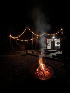 a fire pit in front of a house with lights at Odpoczynek Domki Pod Dębem z Opcją Jacuzzi in Ćmińsk