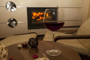 a glass of wine sitting on a table with a fireplace at Family Hotel Saint George in Sofia