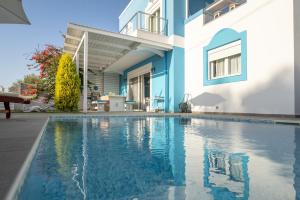 a swimming pool in front of a house at Seabreeze Villa - with Jacuzzi & heated pool in Mastichari