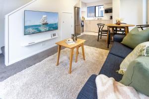 a living room with a couch and a tv on a wall at Inner City Delight walk to Cathedral Square in Christchurch