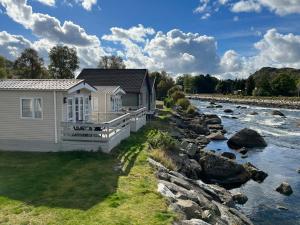 a cottage next to a river with rocks at NAF Steinsnes Camping in Egersund
