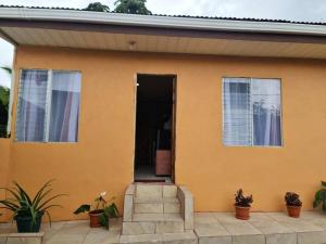 une maison jaune avec des plantes devant dans l'établissement Apartment Guayabon #1, AC, Arenal Volcano Fortuna, à Fortuna