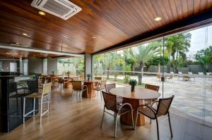 a restaurant with tables and chairs and large windows at Quality Hotel Jundiaí in Jundiaí