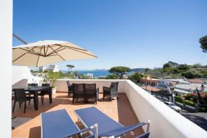 einen Balkon mit einem Tisch, Stühlen und einem Sonnenschirm in der Unterkunft La Baia Blu - Ischia in Ischia