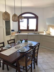 eine Küche mit einem Holztisch mit Stühlen und einem Esszimmer in der Unterkunft Casa Su Soli Sardu 10 - Mit Blick aufs Meer! in Codaruina