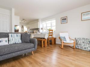 a living room with two couches and a kitchen at Pilchard Cottage in Penzance
