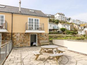 a patio with a wooden table and two benches at Pilchard Cottage in Penzance