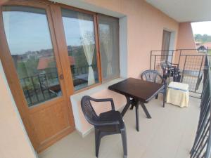 a balcony with a wooden door and a table and chairs at Prostor Guest House in Byala