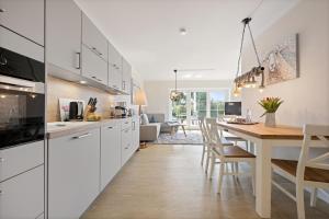 a kitchen with white cabinets and a wooden table at Zum Fährmann 2 Whg 1 EG links in 18356 Pruchten in Pruchten +6 photos