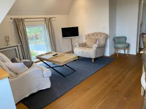 a living room with two chairs and a tv at HofGut Bockelkathen Apartment 3 in Lüdersburg