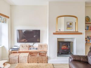 sala de estar con chimenea y TV en Seascape Cottage, en Allonby